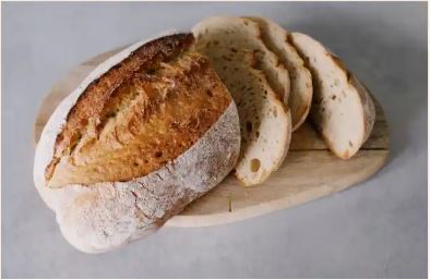 Image of homemade bread, sliced and sitting on a bread board.