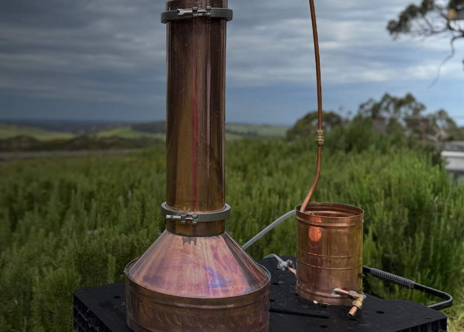 Copper essential oil still sitting in a field of green grass.